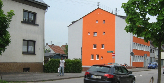 a bright orange apartment block with a gentleman walking in front